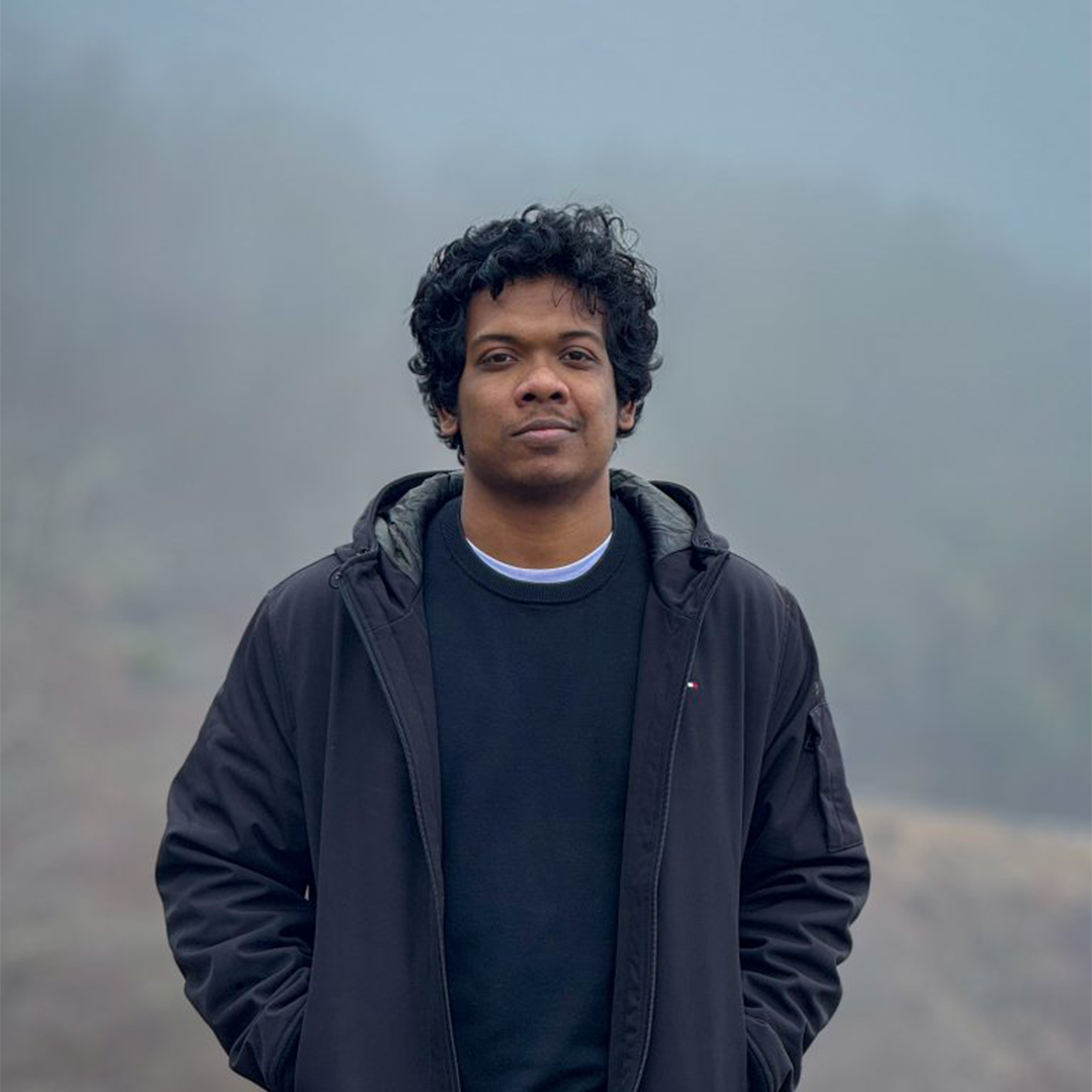 headshot of a man with brown skin and short black curly hair